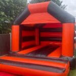An orange and black themed adult bouncy castle side view